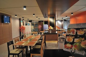 Un restaurante con varias mesas y sillas, una barra con un menú y un televisor colgado en la pared.