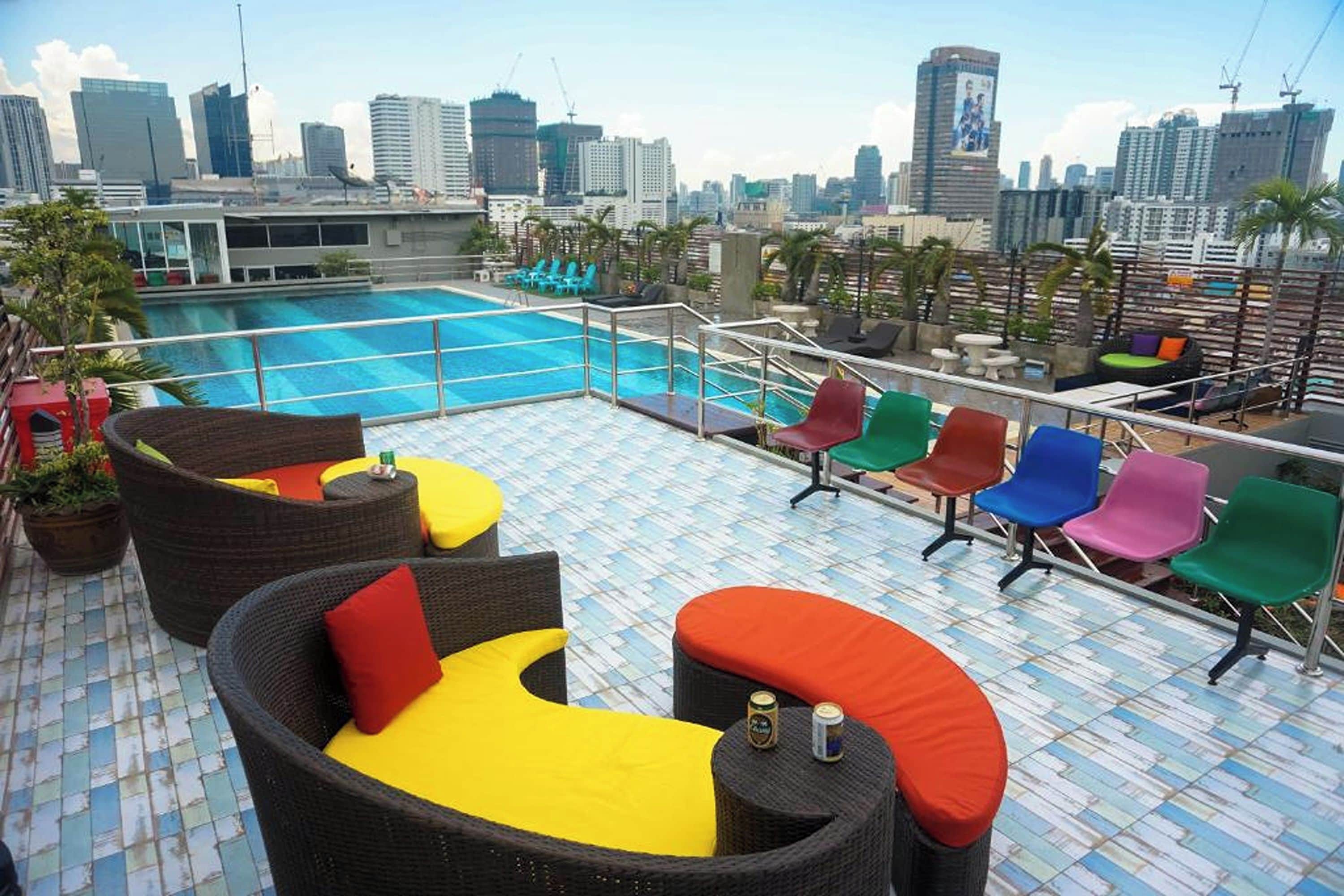 A rooftop pool area with lounge chairs and a city skyline view.