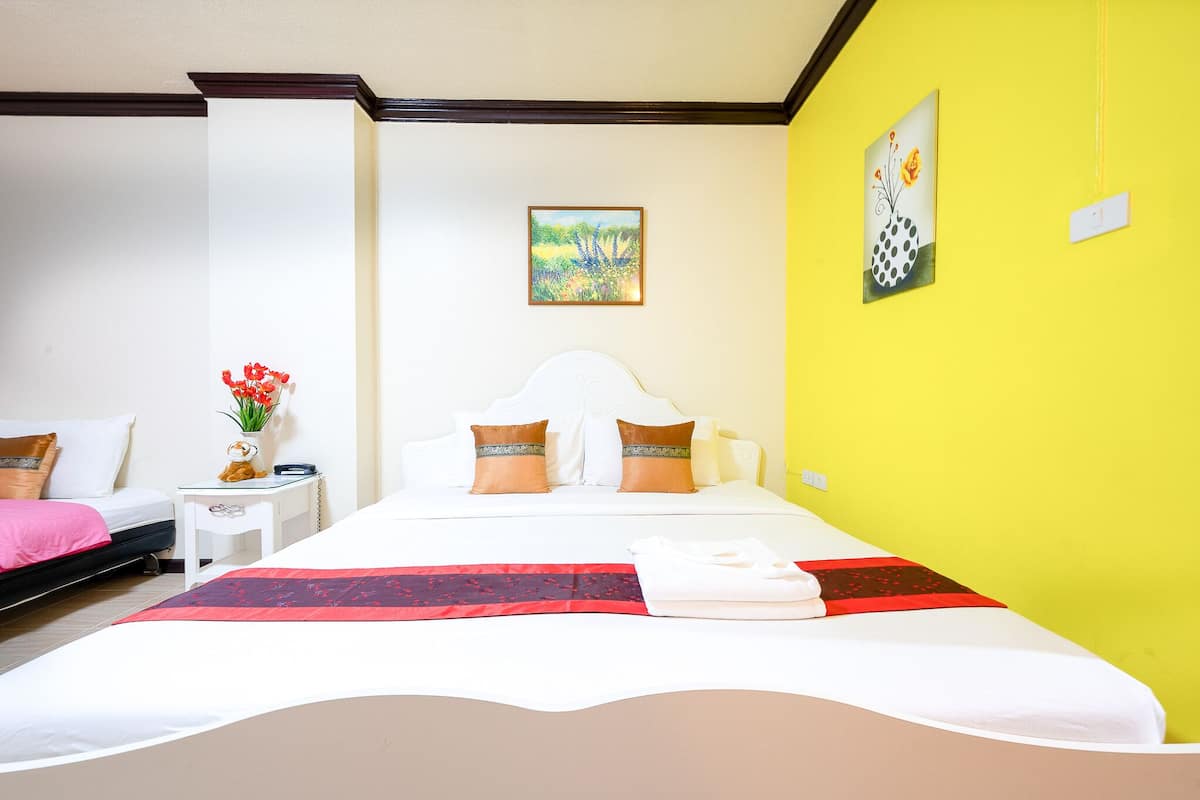 Una habitación de hotel con una cama, una mesita de noche, un florero con flores y dos cuadros en la pared.