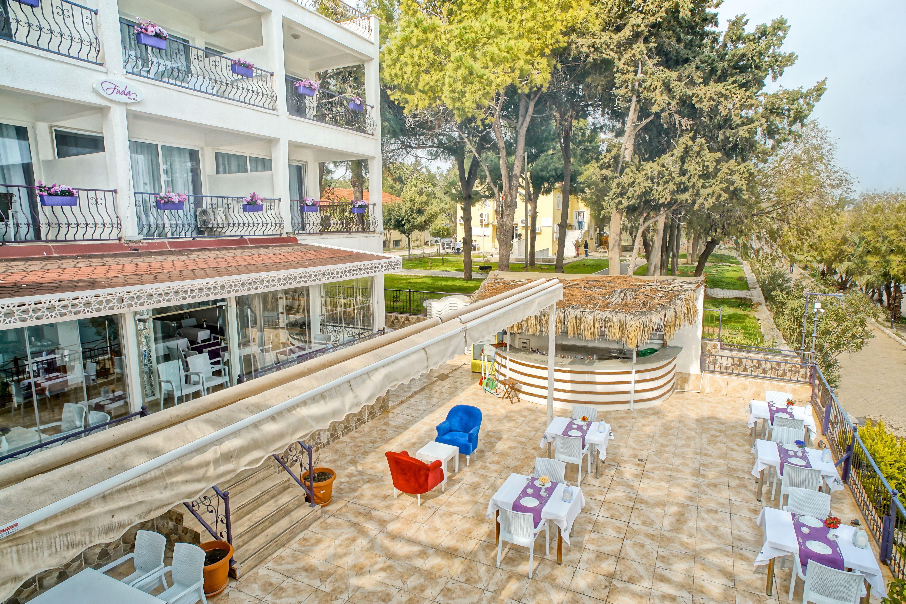 A hotel with outdoor seating, a covered area, and a view of trees and buildings.