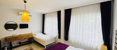 A bedroom with a bed, a bedside table, a TV, a mirror, and a window with curtains.