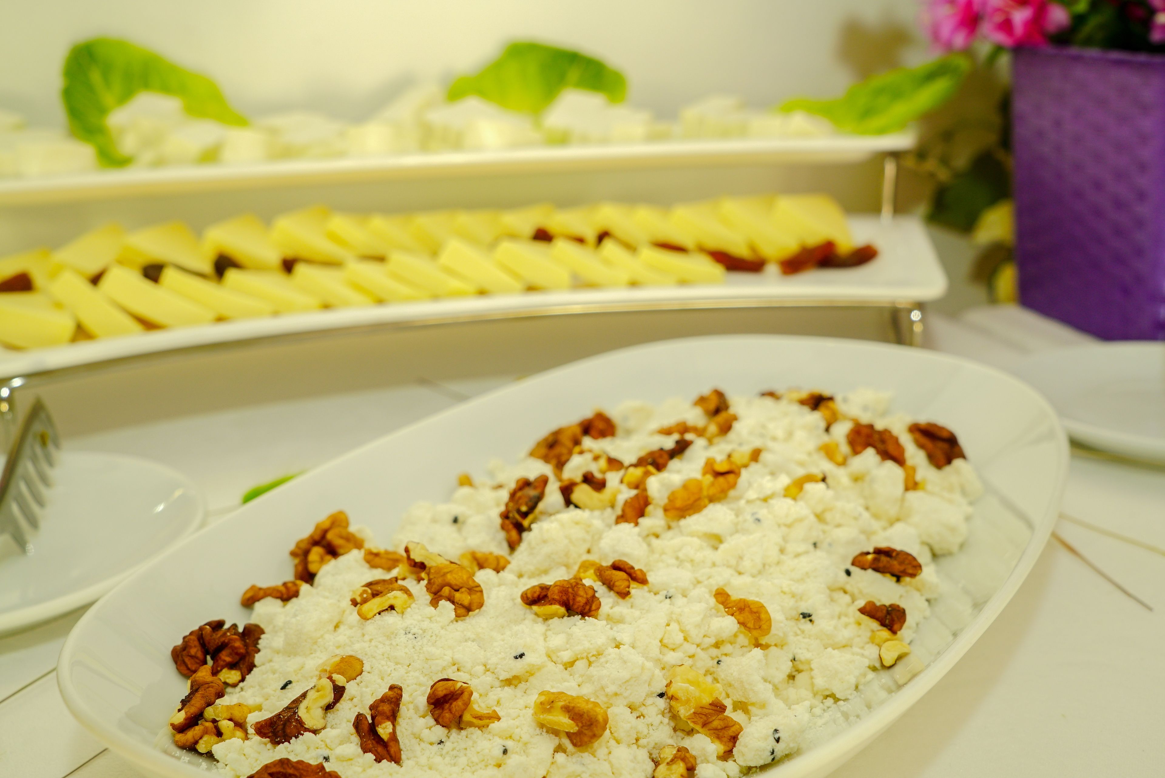A buffet with various dishes, including a plate with a white creamy dish topped with walnuts.