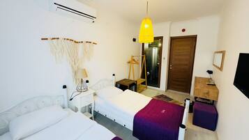 Habitación de hotel con cama, mesitas de noche, lámpara, decoración de macramé en la pared, armario y televisor.