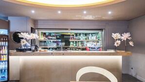 A bar area with a counter, shelves of beverages, and decorative flowers. - The Gate Hotel (Sesto Fiorentino)