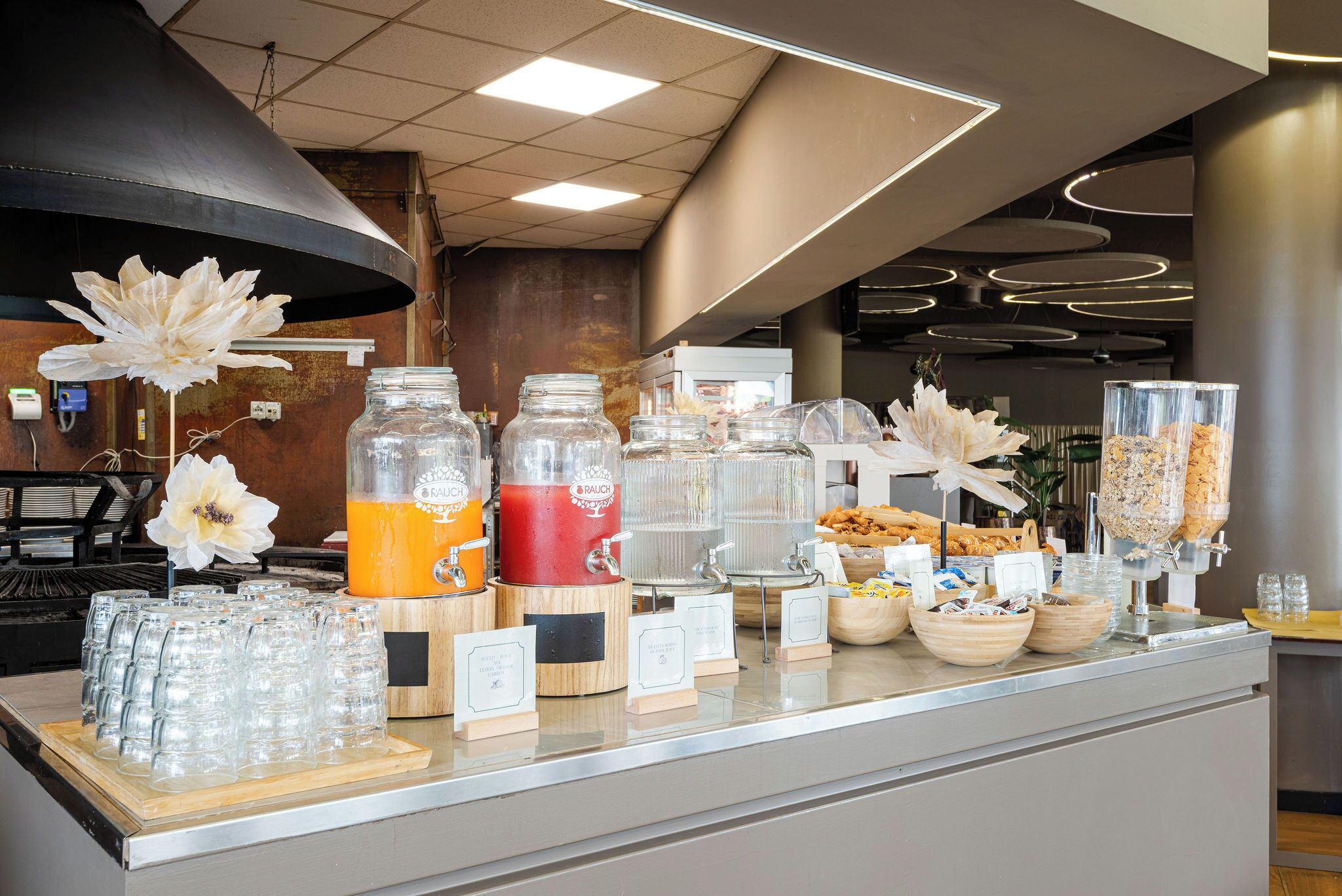 A buffet counter with various food and drink dispensers, including a smoothie maker and a bread dispenser.