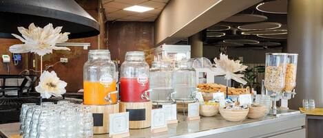 A buffet counter with various food and drink dispensers, including a smoothie maker and a bread dispenser.