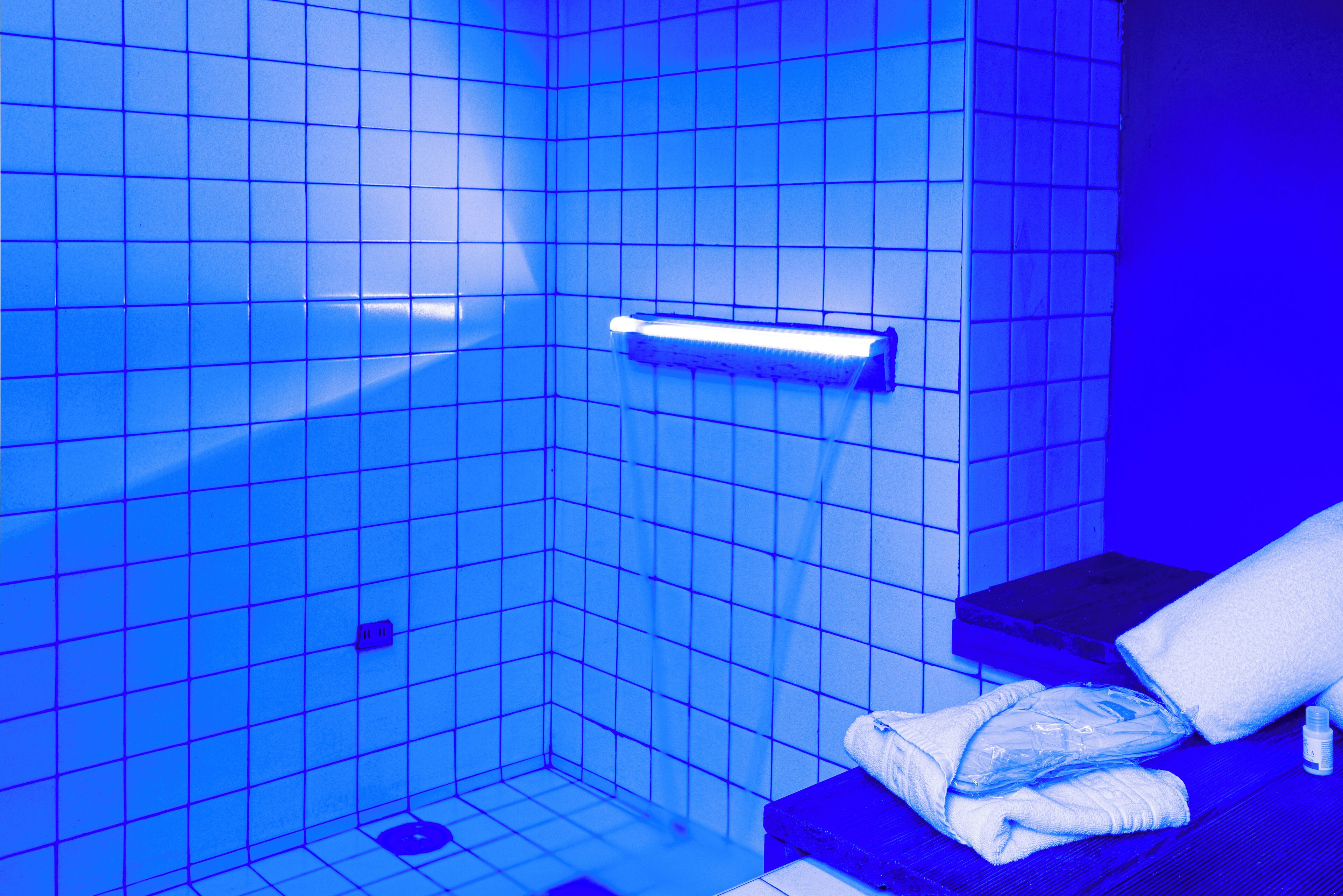 Um banheiro com paredes azulejadas em azul, um porta-toalhas e uma pequena prateleira.