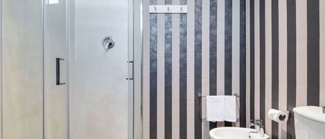 A modern bathroom with a glass shower enclosure, a sink, and a toilet.