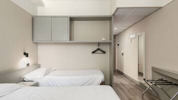 A hotel room with two beds, a wardrobe, a hanging clothes rack, and a mirror.