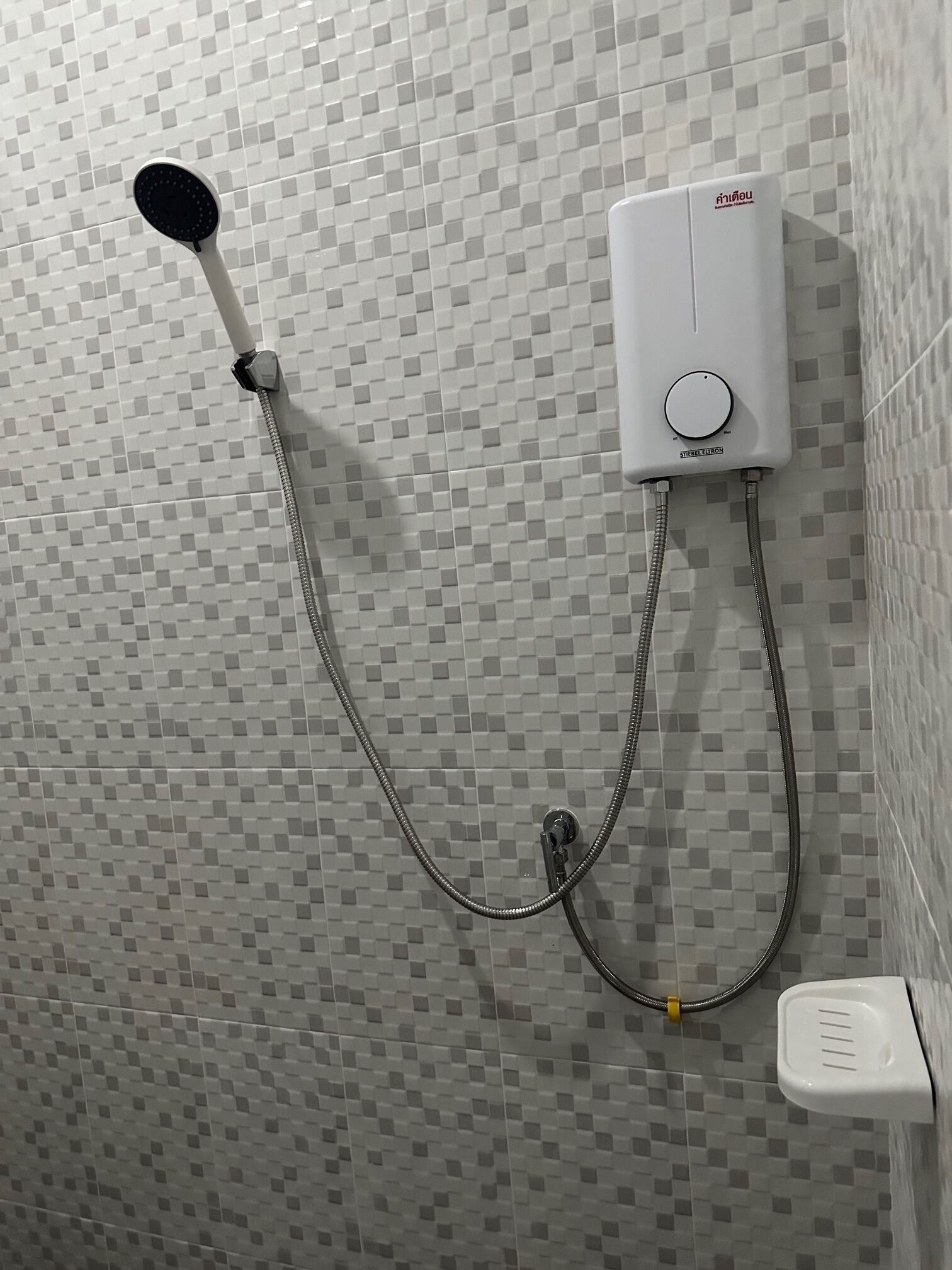 A shower with a handheld showerhead and a wall-mounted control unit.