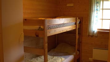 A bunk bed room with wooden walls and a ceiling light.