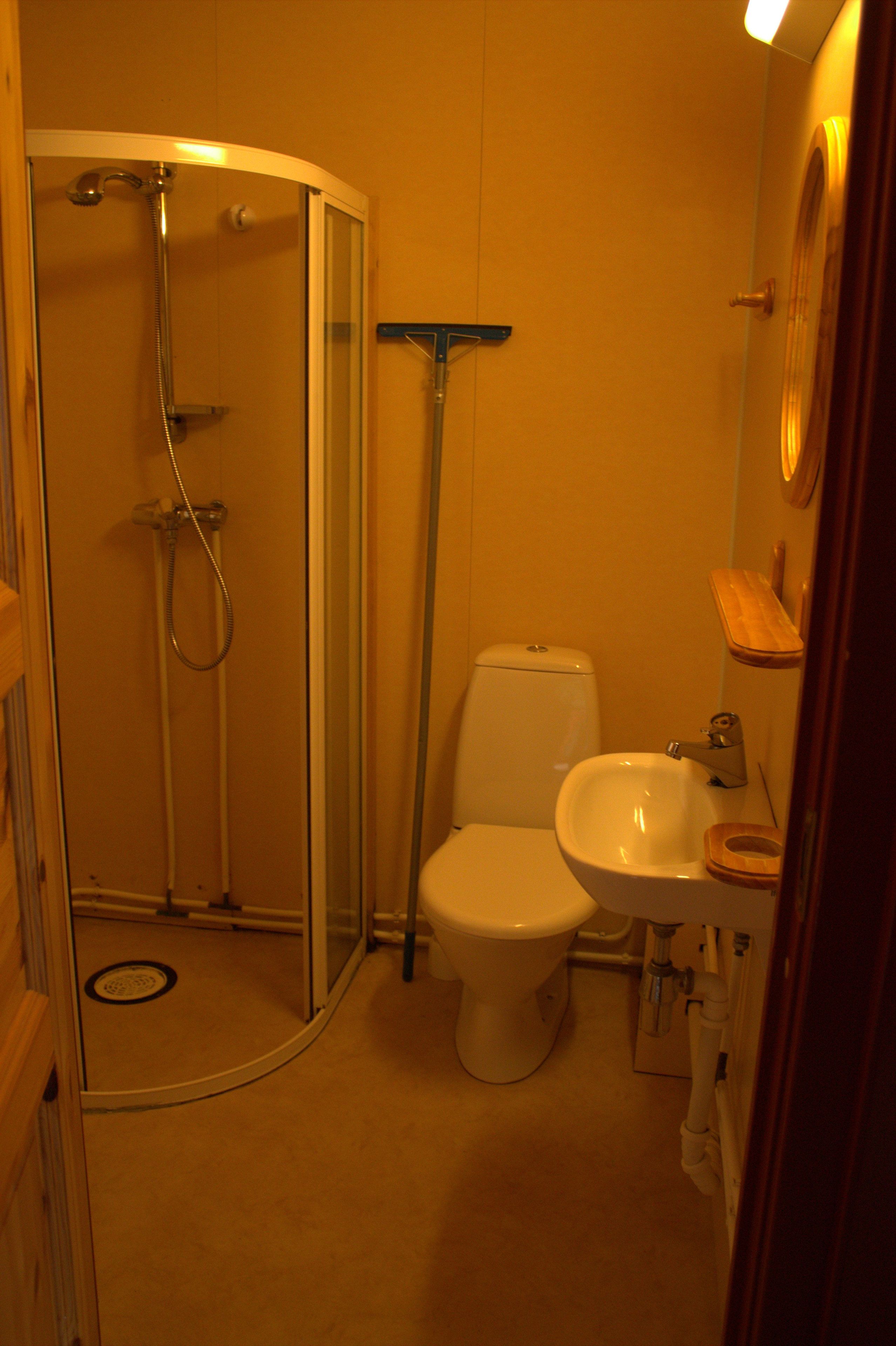 Un baño compacto con ducha de vidrio, inodoro y lavamanos.