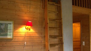 A wooden interior with a sofa, a red wall lamp, and a wooden staircase. - Sjøholt Camping (Ålesund)