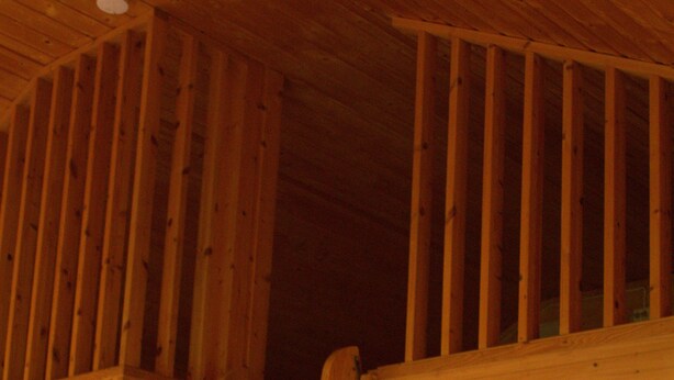 A wooden staircase leading to a loft area with a sloped ceiling and a light fixture on the wall. - Sjøholt Camping (Ålesund)