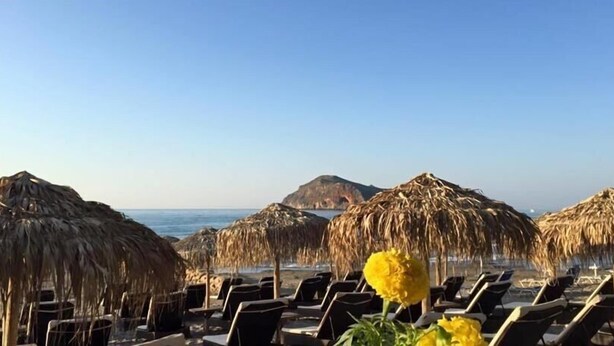 A beach with thatched umbrellas and lounge chairs facing the sea. - Troulakis Beach Hotel (Chania)
