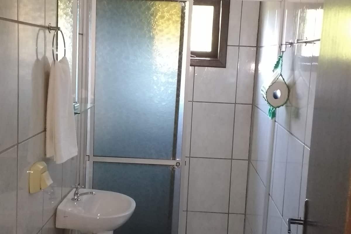 A small bathroom with a toilet, sink, and shower.