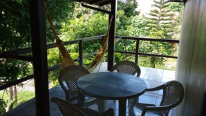A covered outdoor seating area with a table and chairs, surrounded by lush greenery. - Hospedaria Ondas do Rosa (Garopaba)