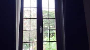 A dark wooden door with a white handle, leading to a window with a view of greenery outside.