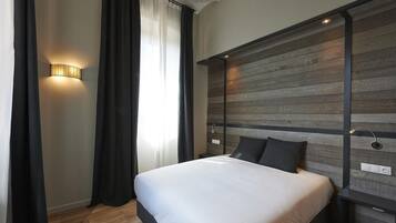 Une chambre à coucher moderne avec une tête de lit en bois, un grand lit avec une literie blanche et un luminaire fixé au mur.