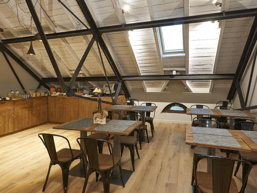 A dining area with wooden tables and chairs, a kitchen area with a wooden counter, and a sloped ceiling with skylights.