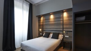 A modern bedroom with a large bed, wooden headboard, bedside lamps, and a built-in bench. - Hotel Parada Puigcerdà (Puigcerda)