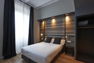 Un dormitorio moderno con una cama grande, cabecero de madera, lámparas de noche y un banco empotrado.