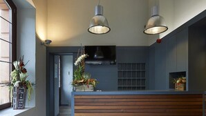 A reception area with a wooden counter, two pendant lights, and a TV. - Hotel Parada Puigcerdà (Puigcerda)