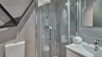 Une salle de bain moderne avec une douche à parois de verre, un lavabo blanc et des toilettes.