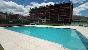 A modern building with a swimming pool, surrounded by a paved area.