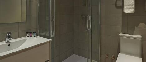 A modern bathroom with a glass-enclosed shower, a white sink, and a toilet.