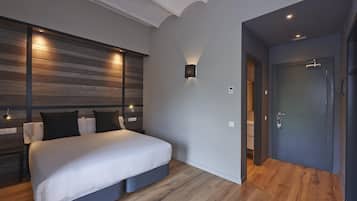 A modern bedroom with a bed, wooden panel wall, and a door to a bathroom.