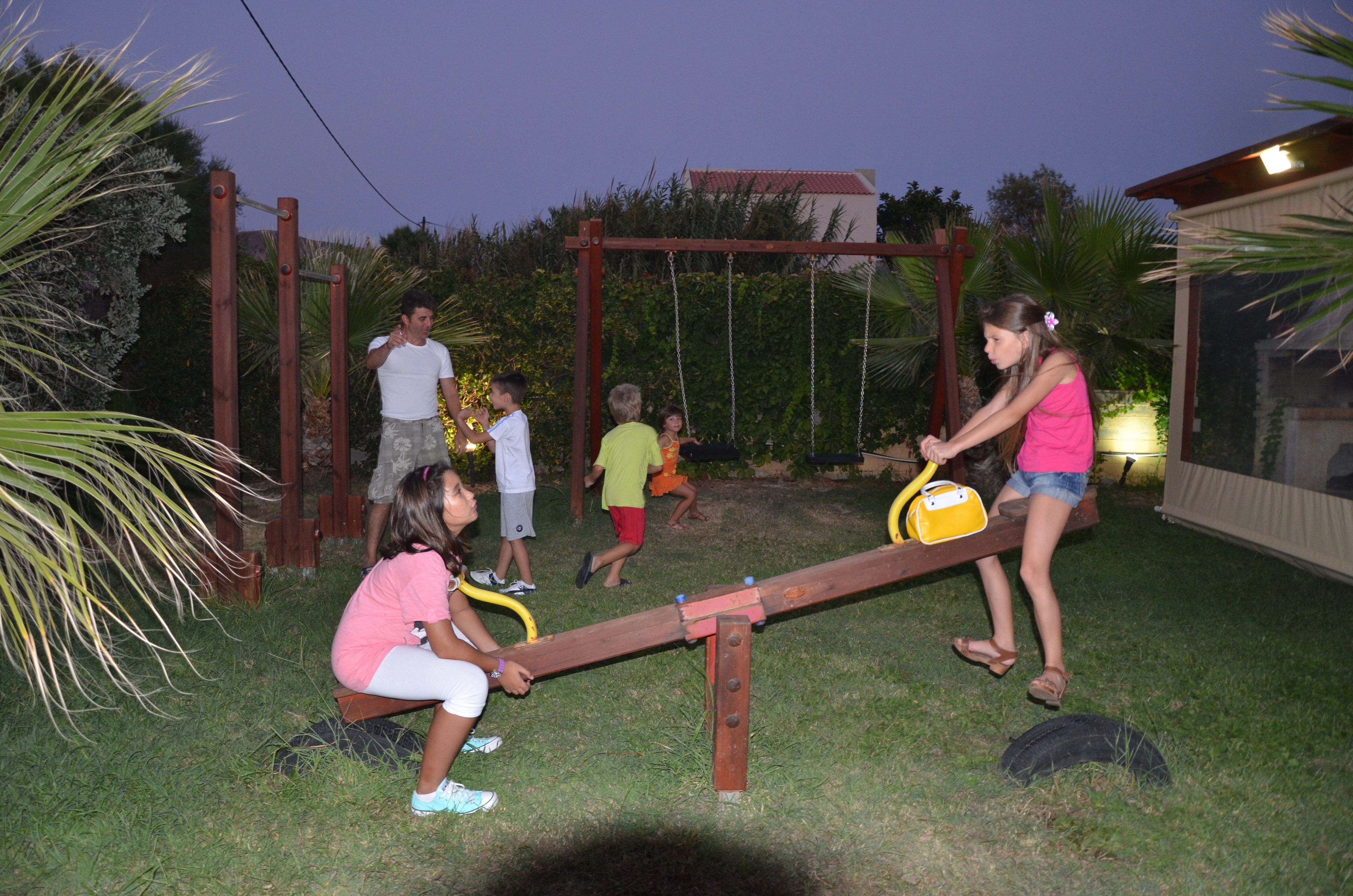Bambini che giocano sull'altalena in giardino, con un'altalena in legno e un'amaca.