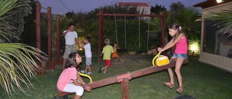 Bambini che giocano sull'altalena in giardino, con un'altalena in legno e un'amaca.