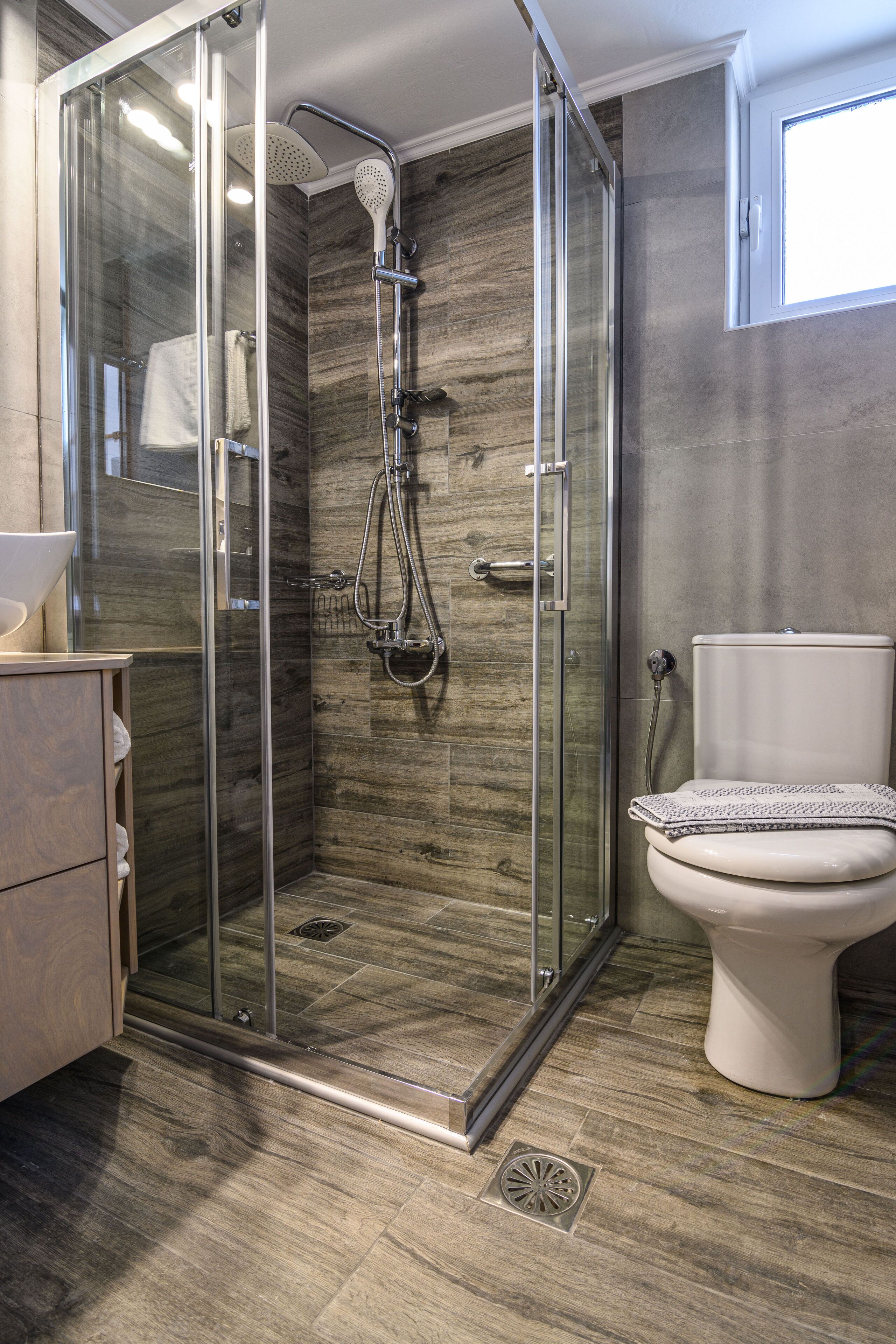 A modern bathroom with a glass-enclosed shower, a toilet, and a vanity with a sink.