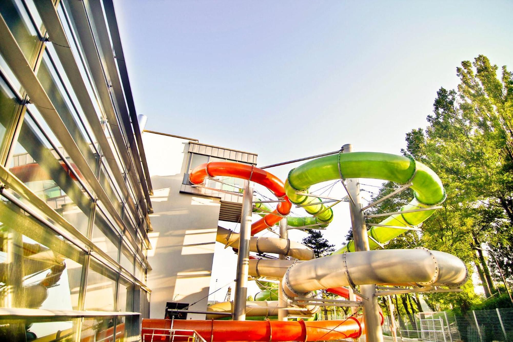 Ein Wasserpark mit mehreren Rutschen und einem Gebäude mit großen Fenstern.