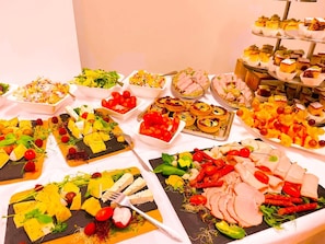 Un bufé con diversos alimentos, como ensaladas, frutas y carnes.