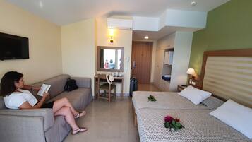 A hotel room with a sofa, a desk, a bed, and a mirror.