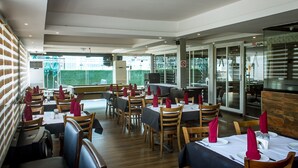 A restaurant with tables set for dining, a bar area, and a view of the outdoors. - Atlantic Hotel And Suites (Lagos)