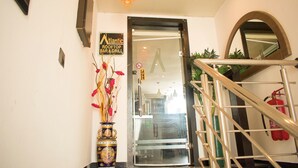 A hotel entrance with a sign for the Atlantic Rooftop Bar & Grill, a staircase with a handrail, and a fire extinguisher on the wall. - Atlantic Hotel And Suites (Lagos)