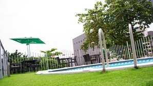 A pool area with a green umbrella, black chairs, and a white fence. - Atlantic Hotel And Suites (Lagos)