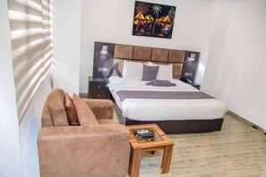 A bedroom with a bed, bedside tables, a sofa, and a coffee table. - Atlantic Hotel And Suites (Lagos)