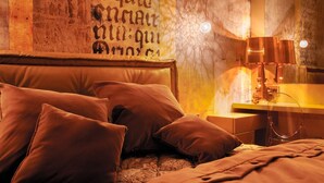 Una cama con varias almohadas y una mesita de noche con lámpara.
