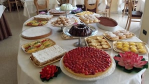Una mesa con diversos postres y pasteles, incluyendo un pastel de chocolate, tartaletas de fruta y tartaletas de limón.