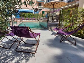 A poolside area with lounge chairs and a pool. - Hotel Zurigo (Varazze)