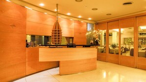 Un área de recepción con un mostrador de madera, una lámpara colgante moderna y un separador de vidrio.