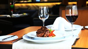 A dining table with a steak, two wine glasses, and cutlery. - Hotel Diego de Almagro Providencia (Santiago)