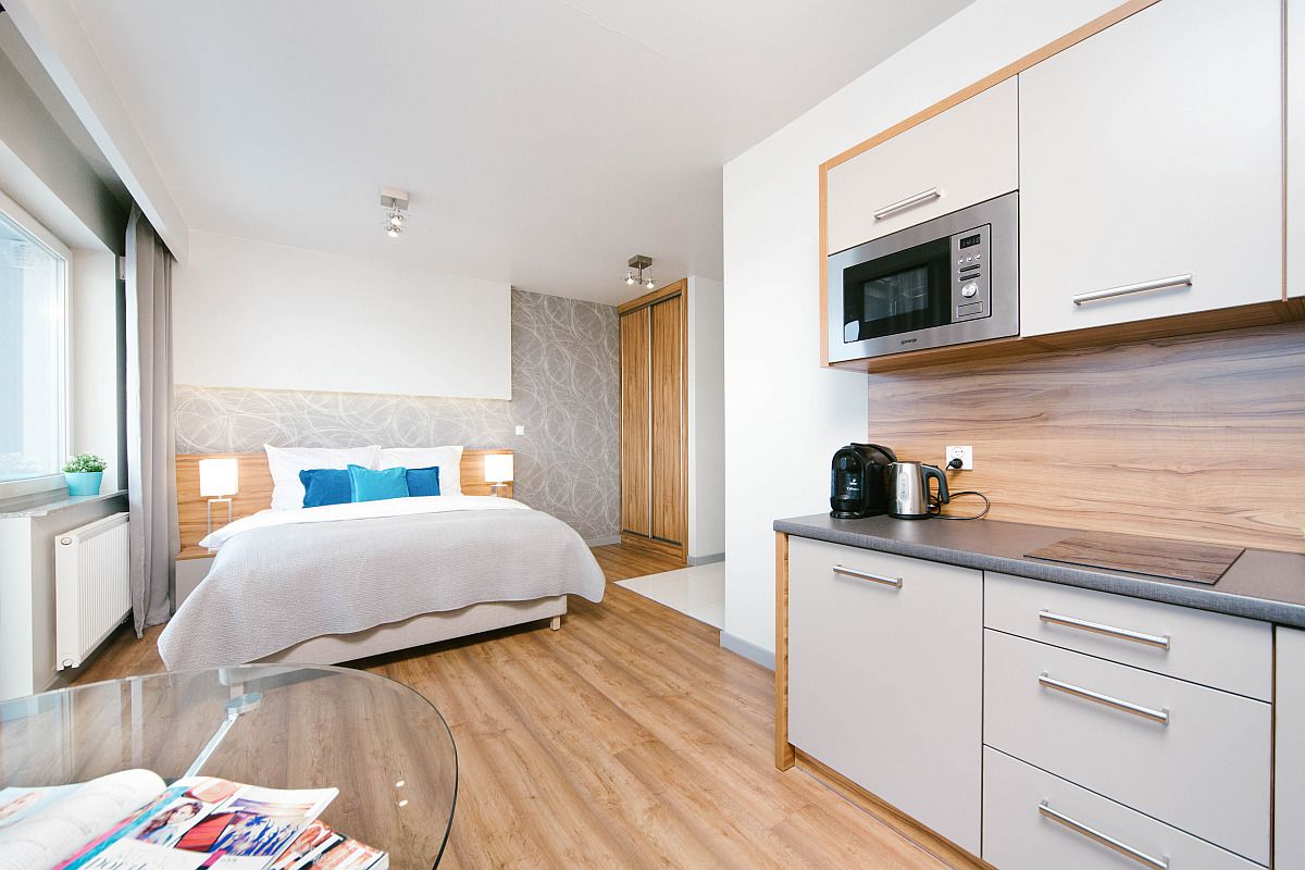 Ein modernes Hotelzimmer mit Bett, Nachttischlampen, einer Kaffeemaschine und einer Küchenzeile mit einer Mikrowelle.