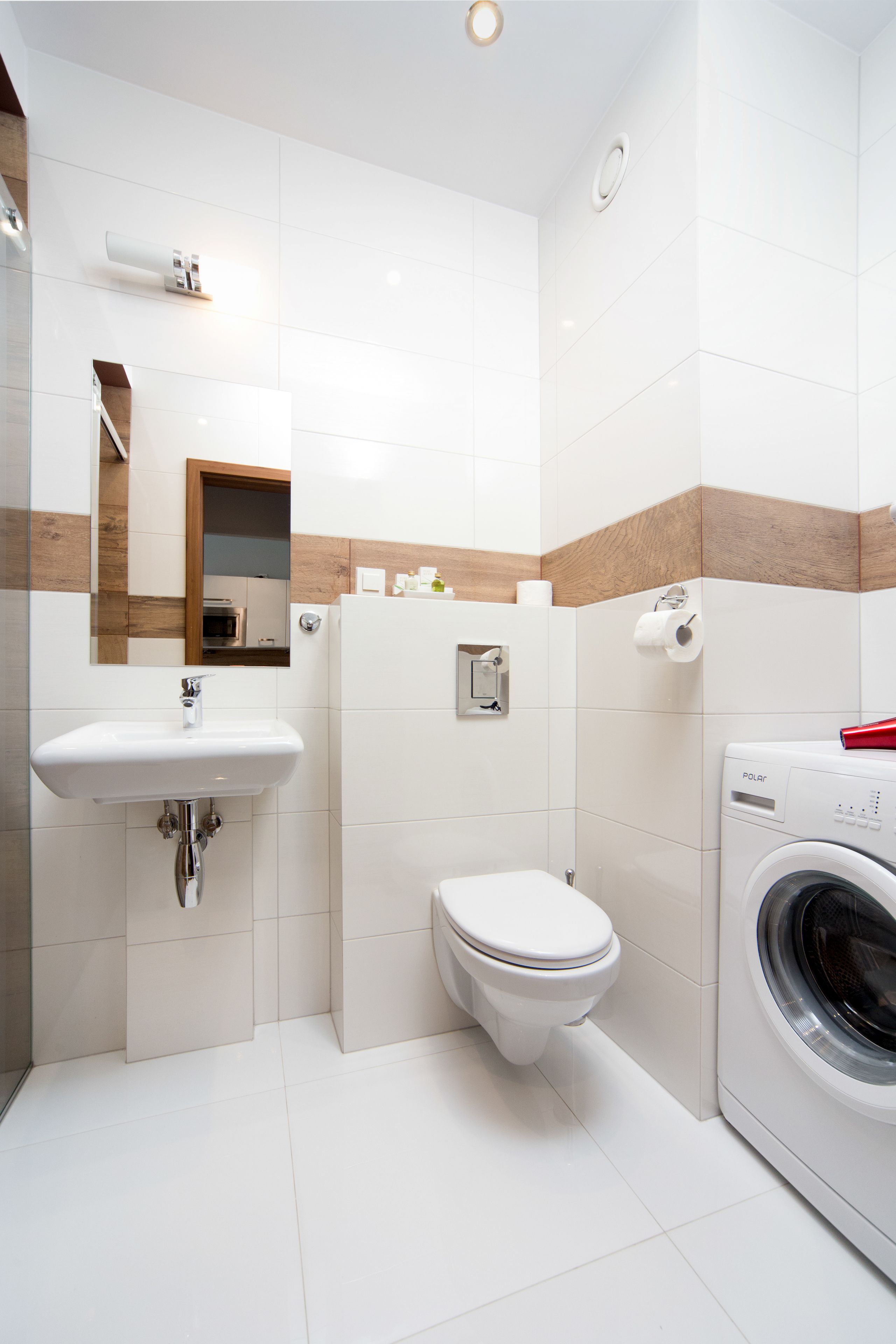 Een moderne badkamer met een wastafel, toilet en wasmachine.