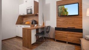 A compact kitchen with a microwave, coffee maker, and a small dining area with a chair. - ActivPark Apartments (Katowice)