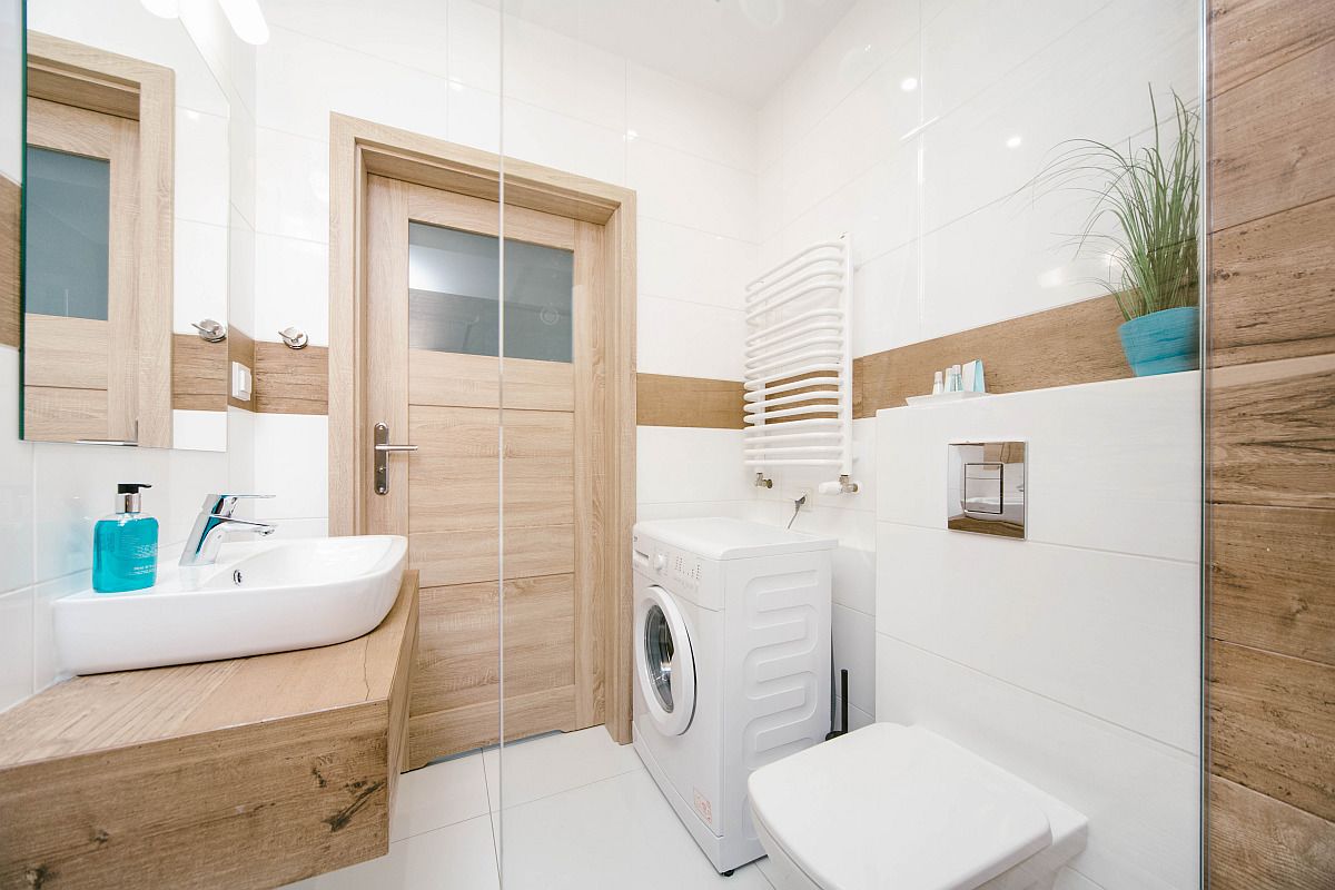 Un baño moderno con un tocador de madera, lavadora e inodoro.